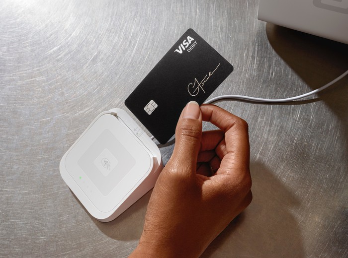 A person inserting their Cash Card into a Square credit card reader.